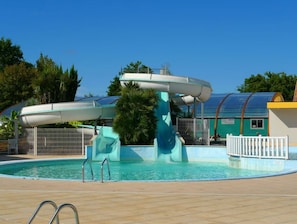 A swimming pool with a water slide and a covered area.