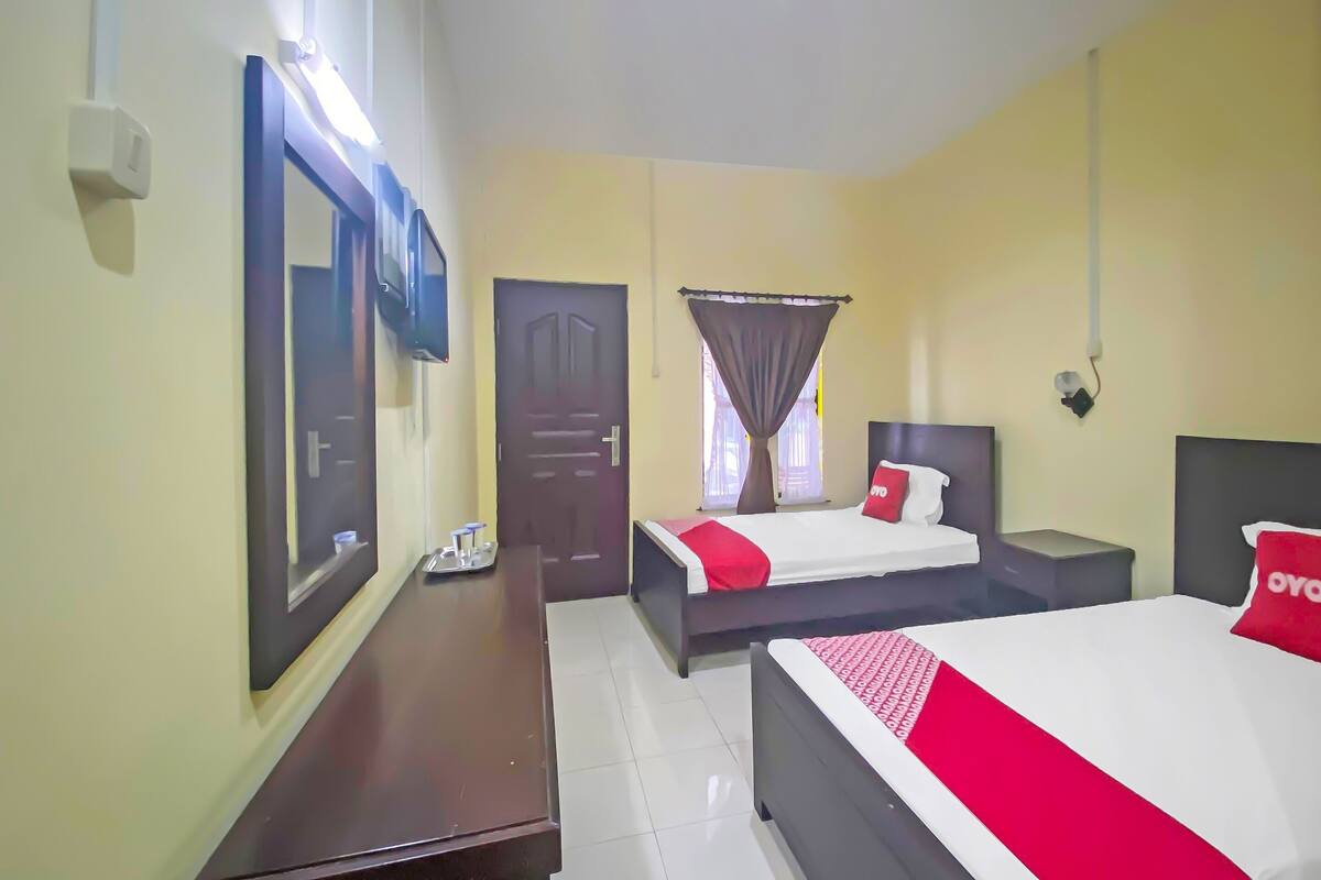 Una habitación de hotel con dos camas, un escritorio, un espejo y una puerta.