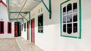 A corridor with white walls, green-framed windows, and red doors. - SPOT ON 91950 Guest House TekNong Syariah (Bangkinang)