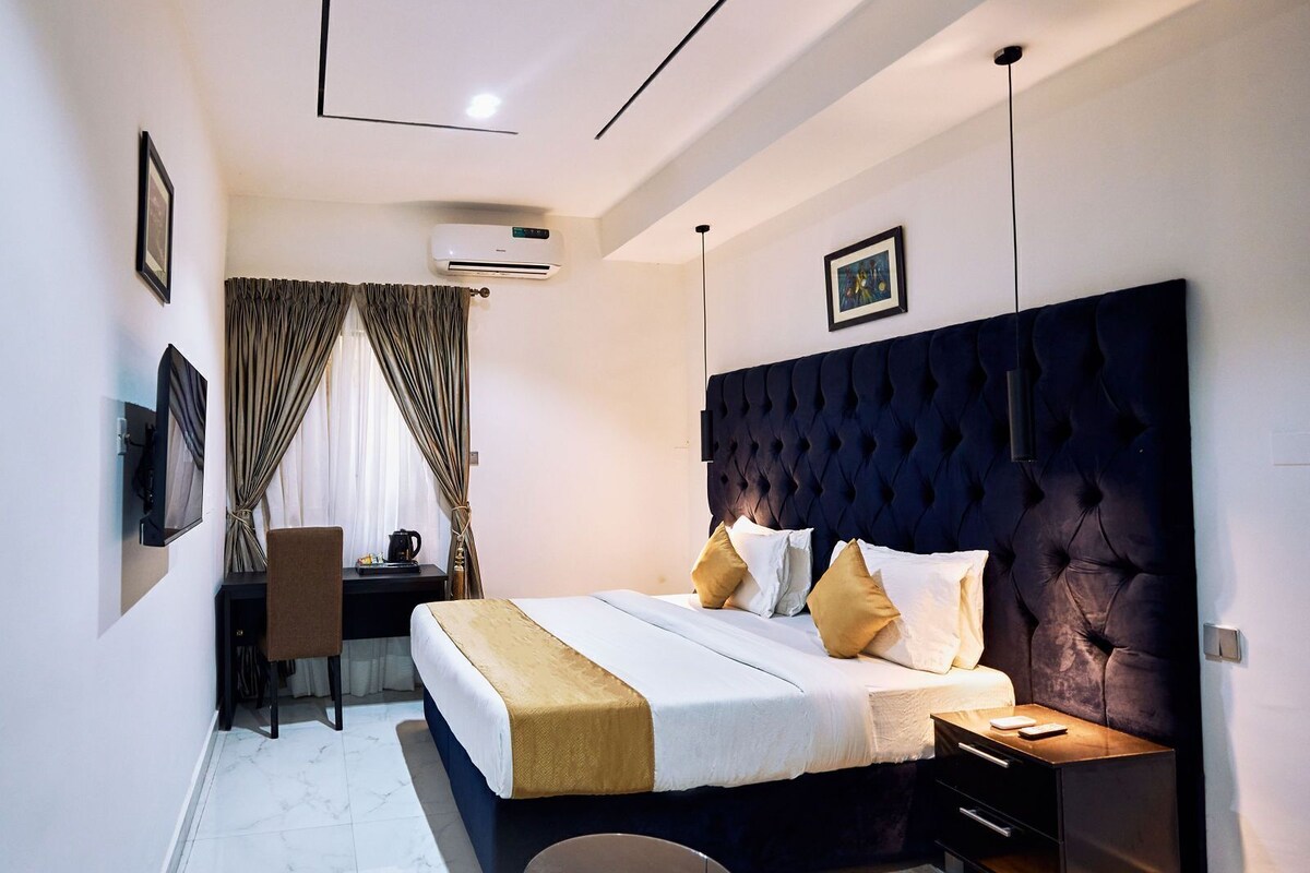 A modern hotel room with a large bed, a desk, and a chair.