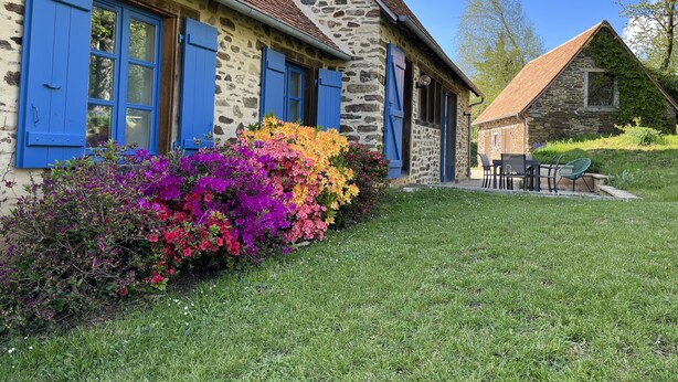 Een stenen huis met blauwe luiken en een stenen schoorsteen.