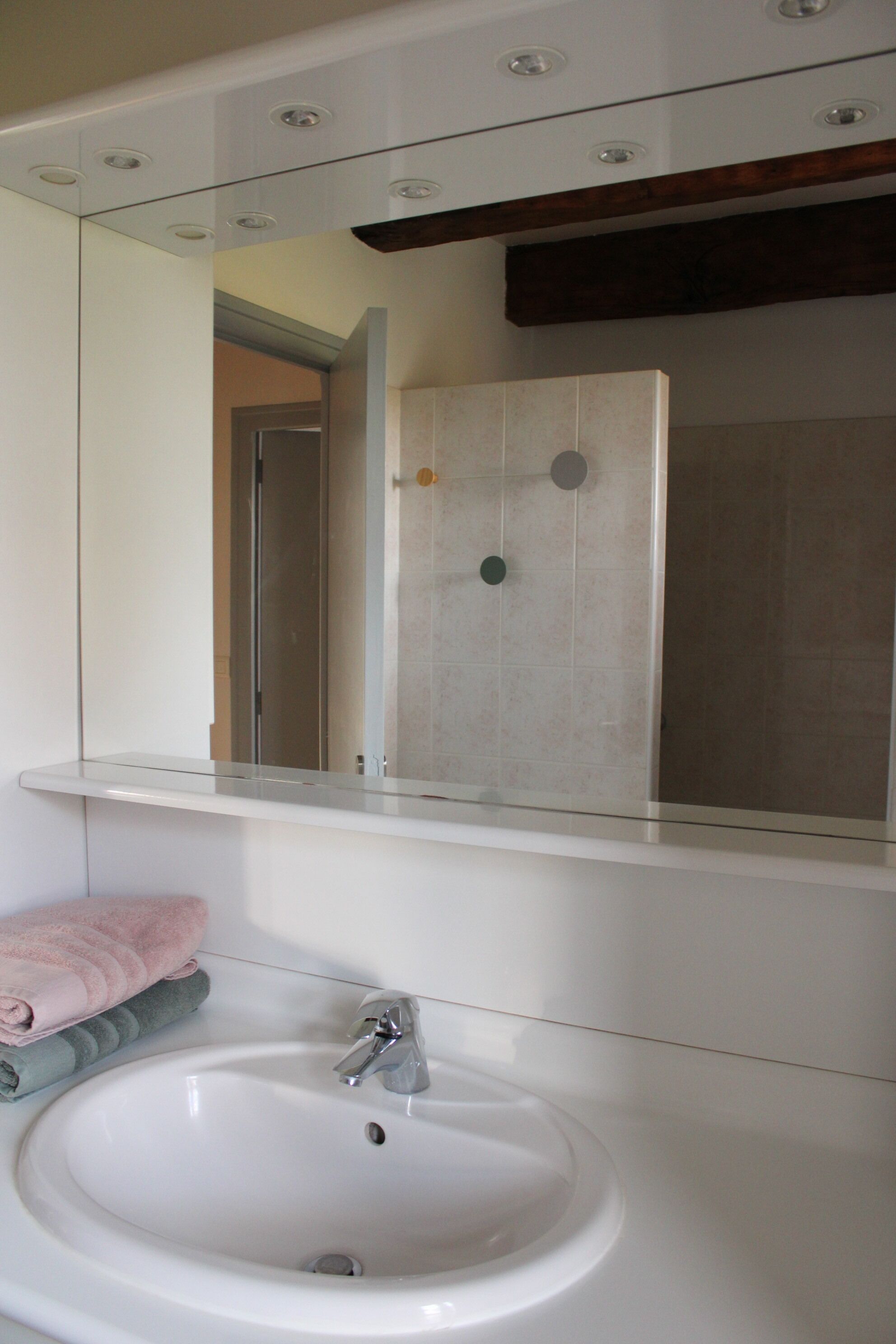 A bathroom with a white sink, a mirror above it, and a towel rack with folded towels.