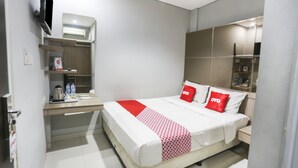 Une chambre d’hôtel moderne équipée d’un lit, de tables de chevet, d’un téléviseur et d’un système de climatisation intégré.