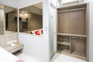 Une chambre d’hôtel avec une grande armoire, une table de chevet avec un téléphone et un miroir.