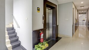 Un hall d’hôtel moderne avec un escalier, un ascenseur et un extincteur.