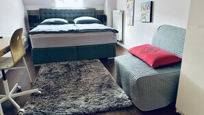 A bedroom with a bed, a desk, a chair, a sofa, and a rug. - Casa Neuenheim (Heidelberg)