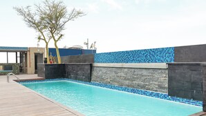 A swimming pool with a wooden deck, surrounded by stone walls and blue-tiled edges. - Cape Royale 213 (Cape Town)