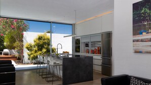 A modern kitchen with a large window, a refrigerator, and a dining area with bar stools.
