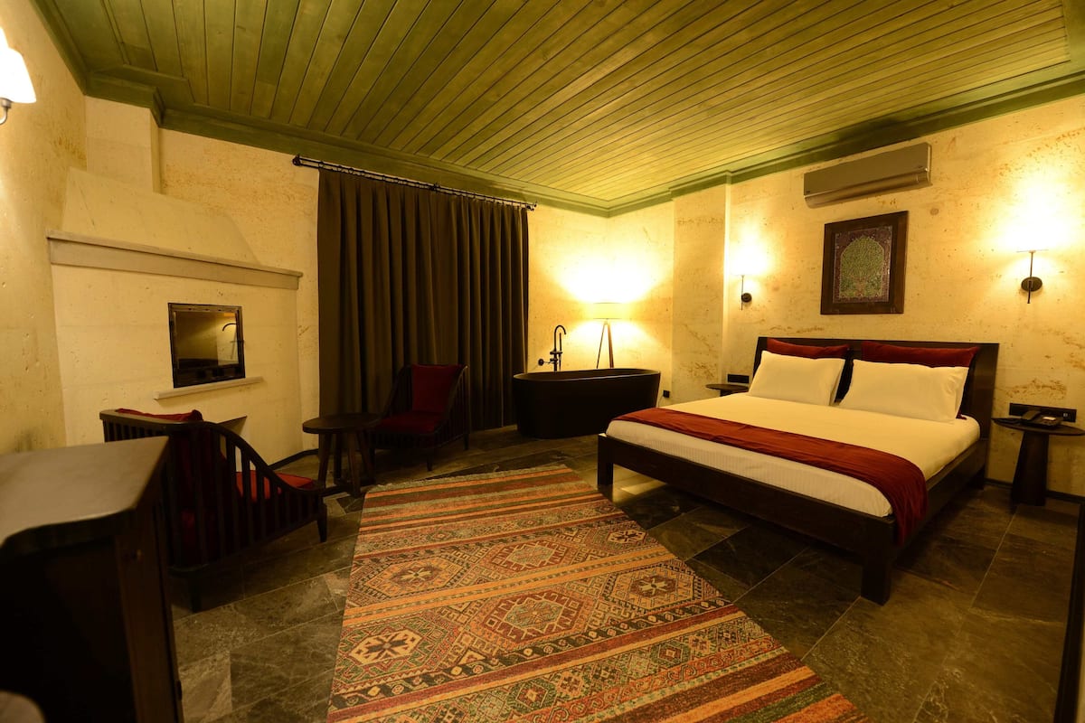 Una habitación de hotel con cama, escritorio, silla, alfombra y aire acondicionado instalado en la pared.