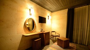 Une chambre d’hôtel avec un bureau en bois, un miroir rond, une télévision et une chaise.