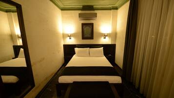Habitació d'hotel amb un llit gran, dues taules de nit, un taulell i un mirall, amb un quadre penjat a la paret.