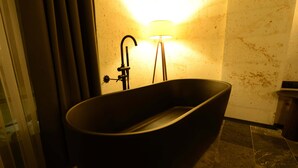 Une salle de bain moderne avec une baignoire sur pieds, un lavabo fixé au mur et un lampadaire.