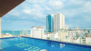 Piscina infinita en la azotea con vistas a un horizonte urbano y un edificio alto.