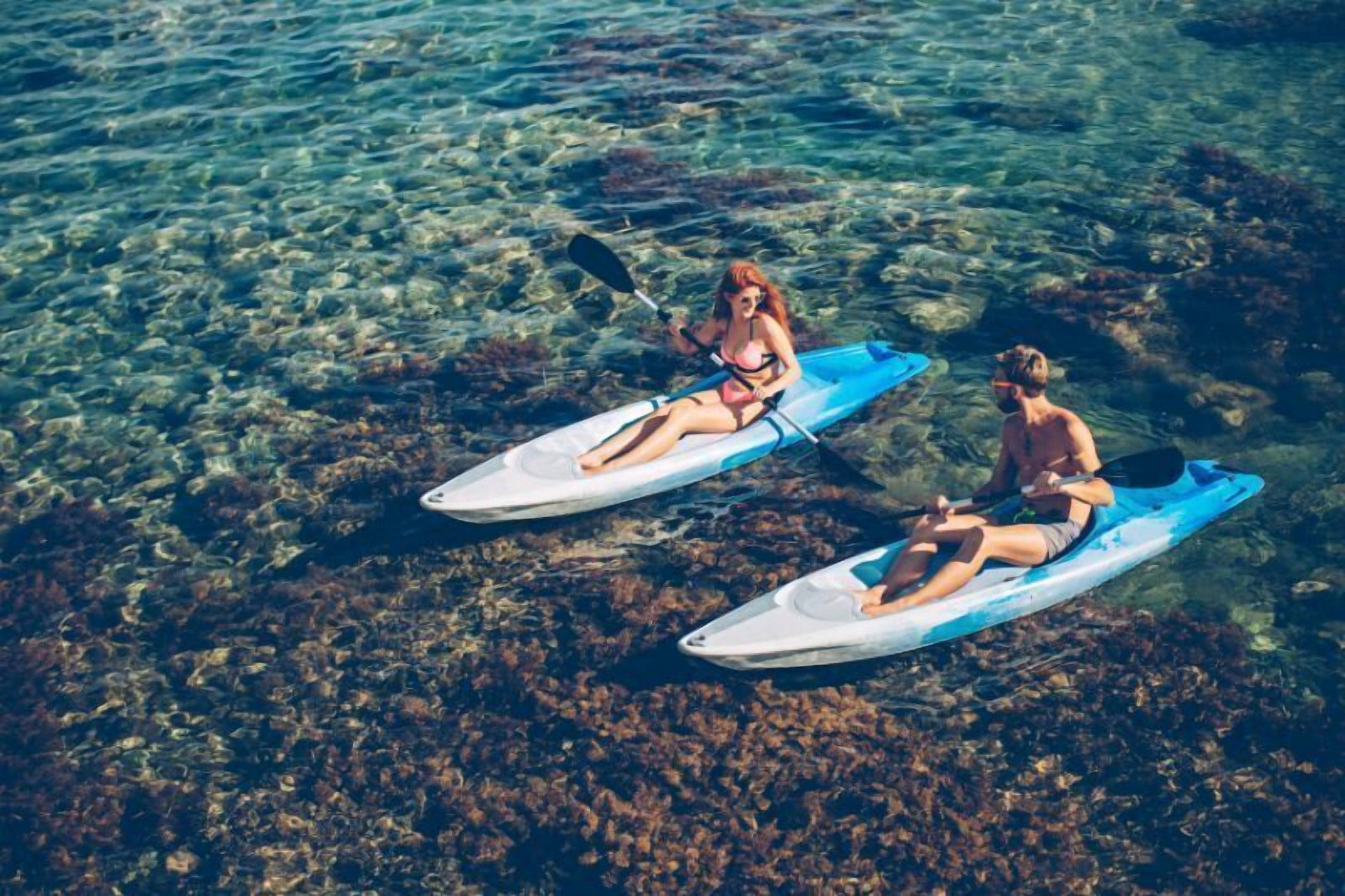 Dos kayaks en un cuerpo de agua clara con rocas visibles bajo el agua.