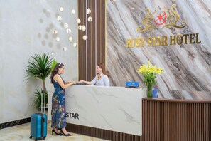 A reception desk at Ruby Star Hotel with a marble wall and a sign. - Ruby Star Hotel Da Nang (Da Nang)