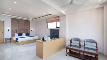 A modern hotel room with a bed, a desk, a TV, and two chairs.
