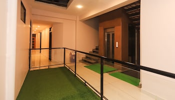 Un interior moderno con barandilla de vidrio, alfombra verde y una escalera que lleva a un ascensor.