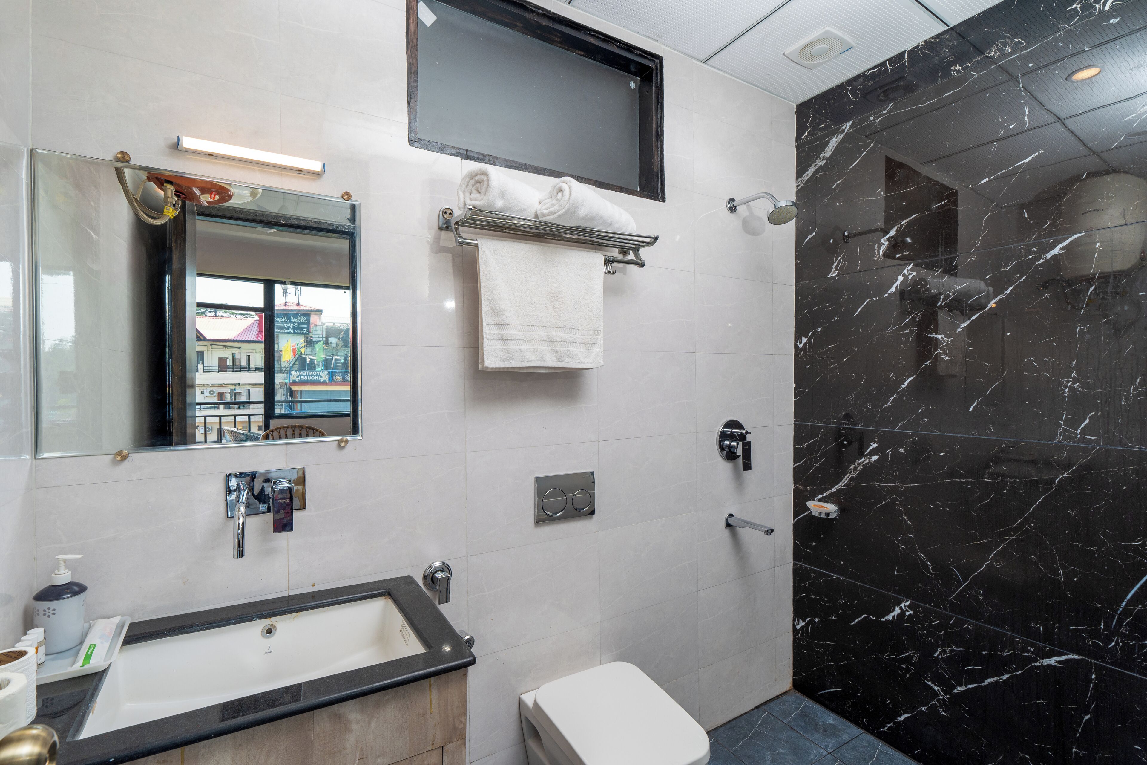 A modern bathroom with a black marble shower, a white sink, and a toilet.