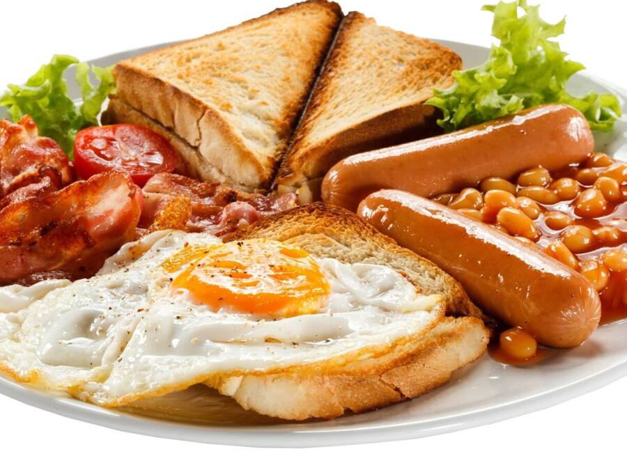 Un plato de comida para el desayuno con tostadas, tocino, huevos, salchichas y alubias guisadas.