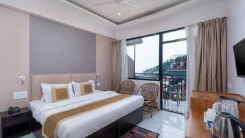 Una habitación de hotel con cama, escritorio con tetera, una silla y televisión.
