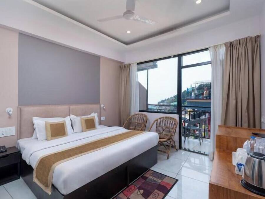 Una habitación de hotel con cama, escritorio con tetera, una silla y televisión.