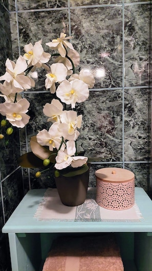 A potted orchid plant on a table with a decorative item beside it. - SOBE RAVNIK (Bled)