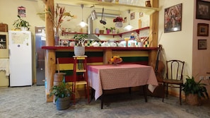 A kitchen with a colorful striped wall, a refrigerator, a stove, and a dining table with a fruit bowl. - SOBE RAVNIK (Bled)