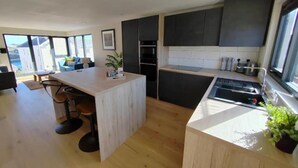 Una cocina moderna con una isla central, armarios oscuros y vistas al exterior.