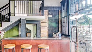 Una zona de bar con mostrador de madera y tres taburetes.