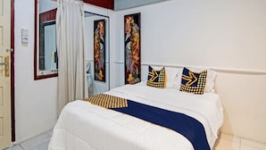 Una habitación de hotel con una cama, un ventanal con cortinas y obras de arte en las paredes.