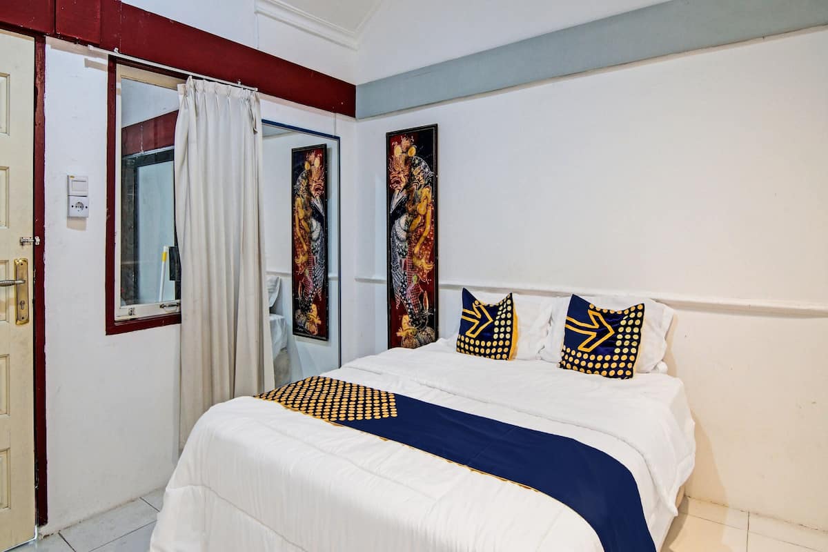Une chambre d’hôtel avec un lit, une fenêtre avec des rideaux et des œuvres d’art accrochées aux murs.