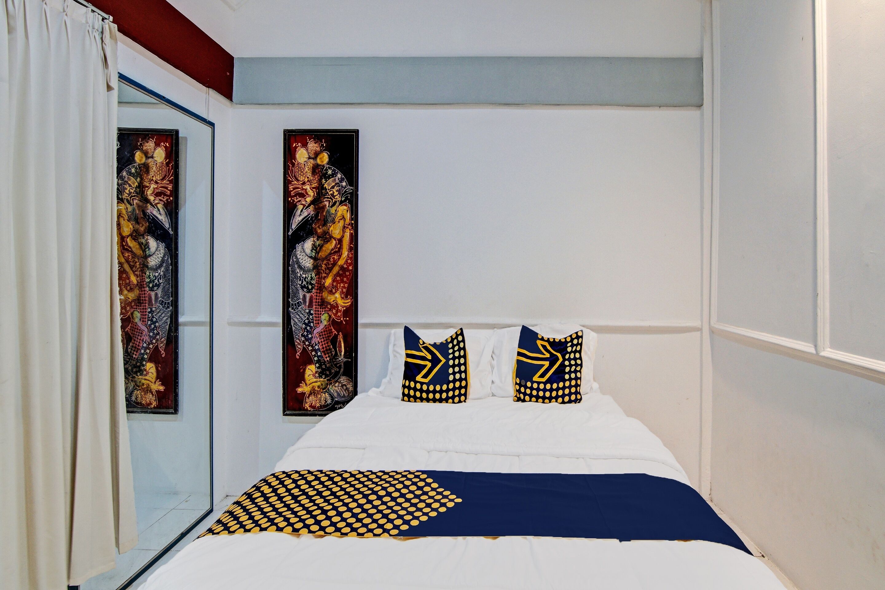 Un dormitorio con cama, dos almohadas, una colcha y un espejo grande.