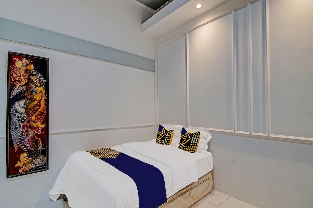 Une chambre à coucher avec un lit, des murs blancs, une grande fenêtre et une œuvre d’art encadrée accrochée au mur.