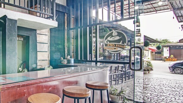 Una zona de bar con taburetes, una barra y vistas a la calle.