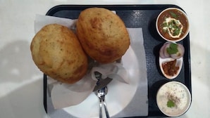 A tray with two fried items, possibly fritters, accompanied by three small bowls of sauces and a spoon. - Diva Pushkar (Pushkar)