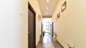 A hotel corridor with marble flooring, potted plants, and framed pictures on the walls. - Diva Pushkar (Pushkar)
