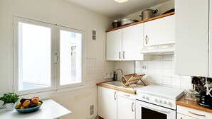 A kitchen with white cabinets, a stove, and a bowl of fruit on the counter.