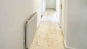 A hallway with a radiator, a 'Smile' sign, and a door at the end.