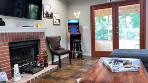 Een woonkamer met een open haard, een televisie, een bar en een groot raam.