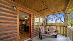 A wooden cabin with a porch, a dining area, and a view of the outdoors.