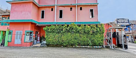 A pink building with a green roof, a staircase, and a signboard.