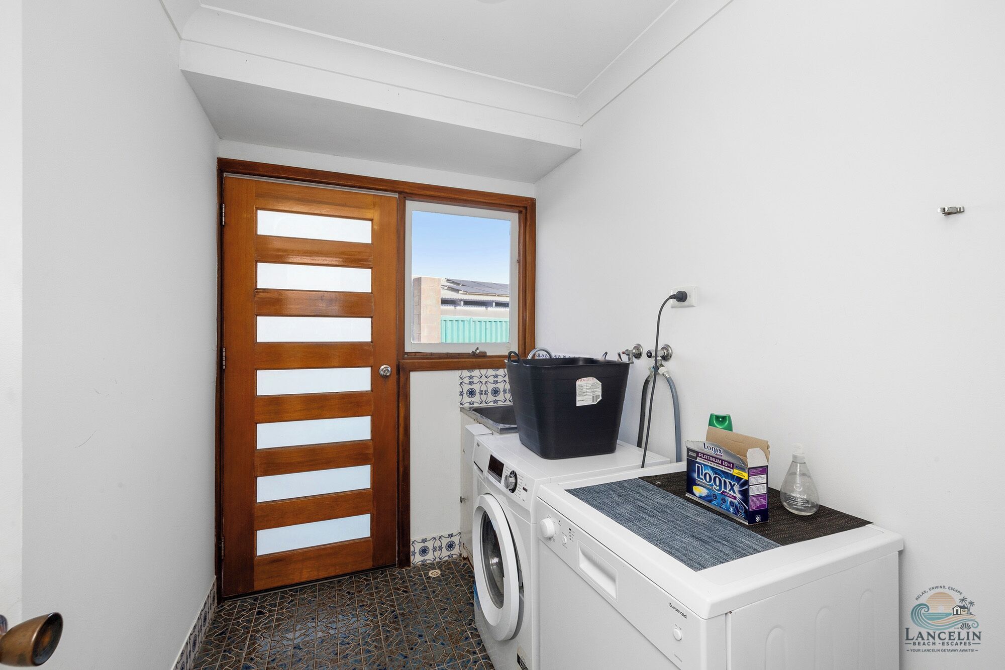 Un espace buanderie comprenant un lave-linge, un sèche-linge et une porte en bois avec une fenêtre.