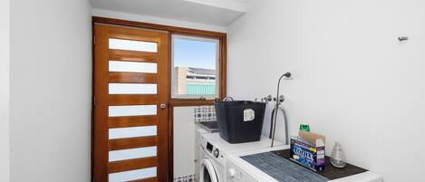 Un espace buanderie comprenant un lave-linge, un sèche-linge et une porte en bois avec une fenêtre.