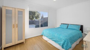 Un dormitorio con cama, armario, ventana y una lámpara en el techo.