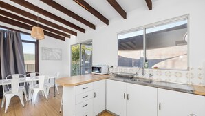 Una cocina con armarios blancos, encimera de madera, un lavabo y una ventana.