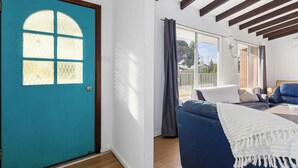 Una habitación con una puerta color turquesa, un sofá azul y una manta blanca.