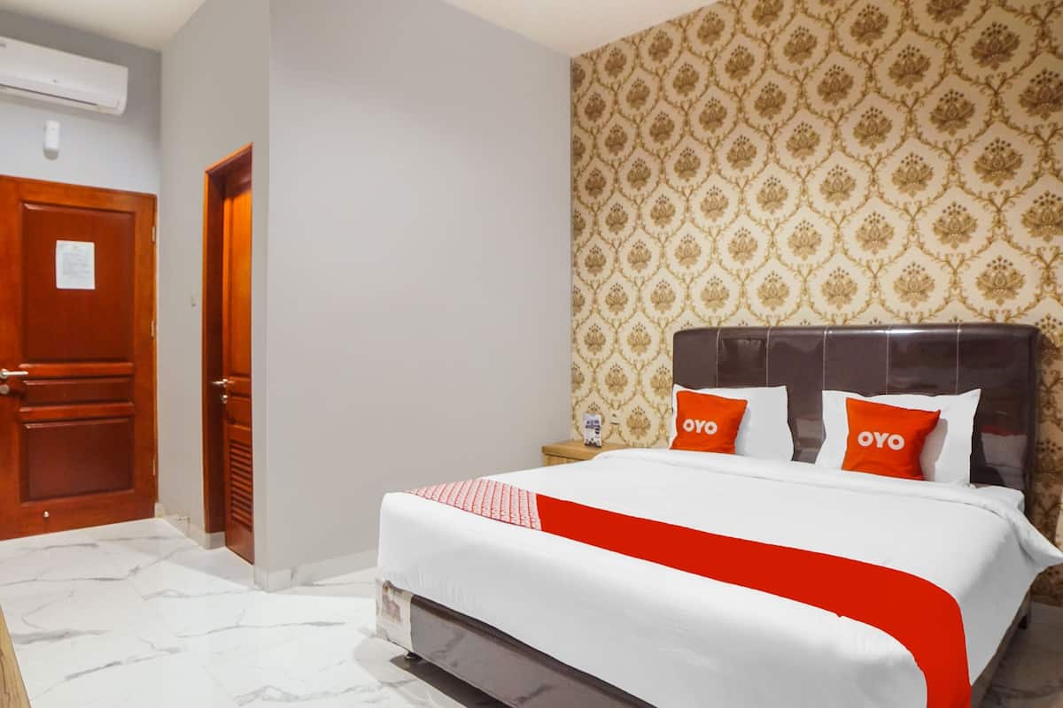 A hotel room with a bed, a wooden door, and a patterned wallpaper.