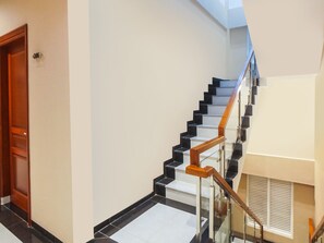 Un escalier moderne avec des marches noires et blanches, des rampes en bois et une balustrade en verre.