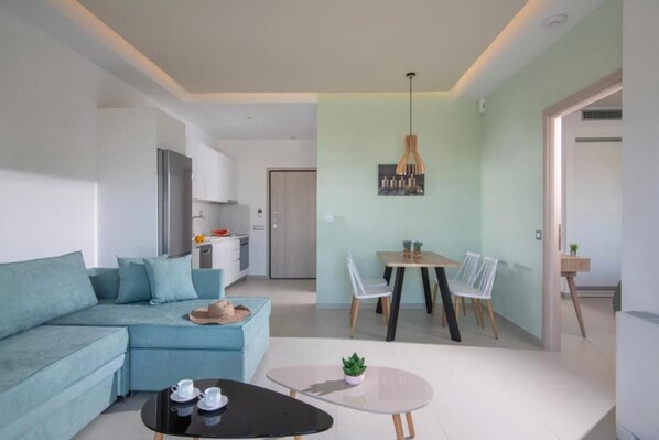 A modern living room with a sofa, a coffee table, and a dining area with chairs and a table.