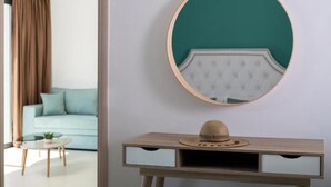 Ein Zimmer mit einem runden Spiegel an der Wand, einem Holzkonsolentisch mit Hut und einem hellblauen Sofa im Hintergrund.